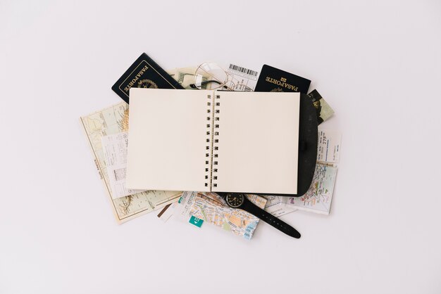 Una vista aérea del cuaderno espiral en blanco en el pasaporte y el mapa aislados sobre fondo blanco