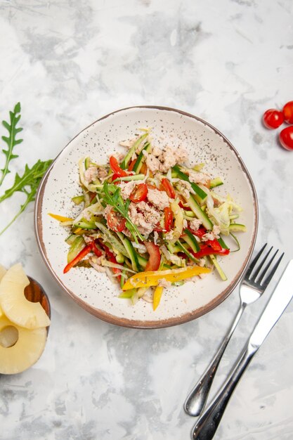 Vista aérea de la deliciosa ensalada de pollo con verduras, tomates, piñas secas, cubiertos en superficie blanca manchada con espacio libre