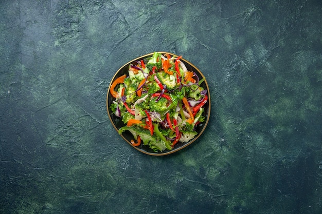 Vista aérea de la deliciosa ensalada vegana en un plato con diversas verduras frescas sobre fondo oscuro