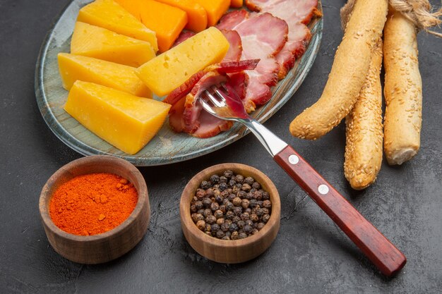 Vista aérea de la deliciosa rebanada de salchicha y queso en un plato azul pimientos sobre un fondo oscuro