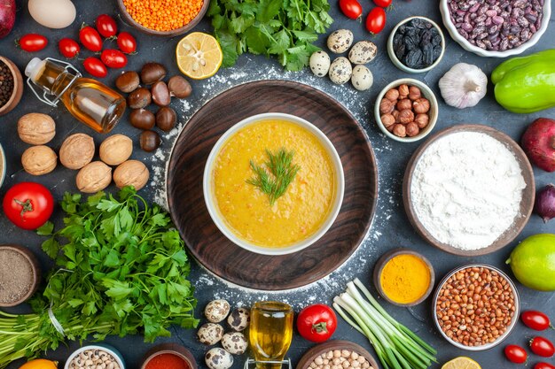 Vista aérea de una deliciosa sopa y especias en un tazón de aceite, verduras, comida, mesa de madera negra rústica