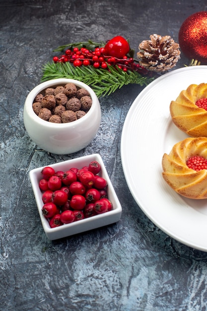 Vista aérea de deliciosas galletas en un plato blanco y decoraciones de año nuevo cornel de regalo en una pequeña olla de chocolate sobre una superficie oscura