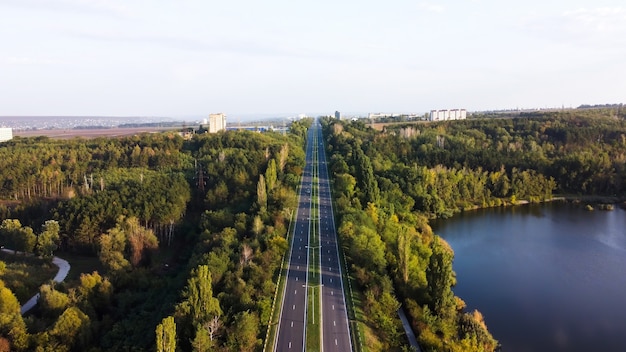 Vista aérea de drone de la naturaleza en Moldavia, camino con un lago y árboles verdes a lo largo de él