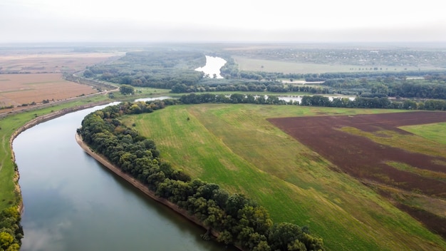 Vista aérea de drone de la naturaleza en Moldavia, río flotante con cielo reflectante, campos verdes con árboles, niebla en el aire