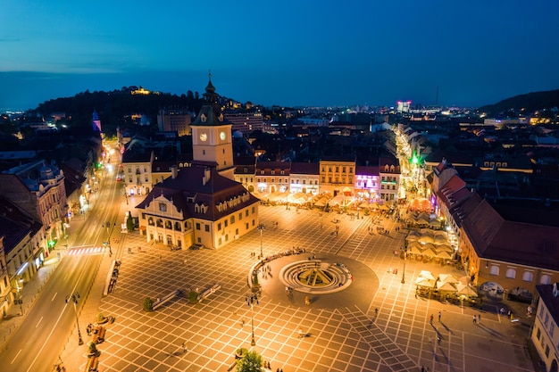 Vista aérea de drones de la Plaza del Consejo en Brasov por la noche Rumania