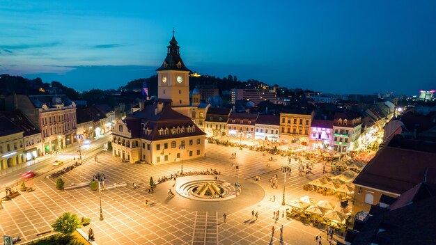 Vista aérea de drones de la Plaza del Consejo en Brasov por la noche Rumania