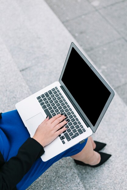 Una vista aérea de la empresaria sentado en la escalera escribiendo en la computadora portátil