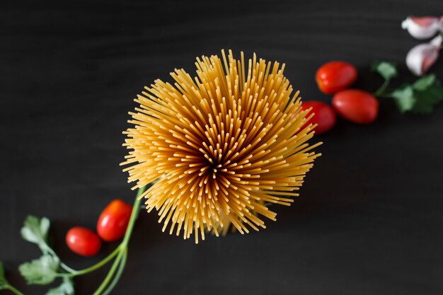 Una vista aérea de espaguetis de pasta sin cocer con ingredientes sobre fondo negro