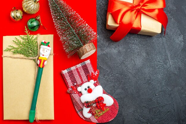 Vista aérea del estado de ánimo navideño con calcetín de regalo de accesorios de decoración de árbol de navidad sobre fondo rojo y negro