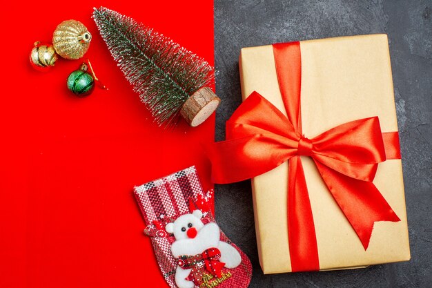 Vista aérea del estado de ánimo navideño con calcetín de regalo de accesorios de decoración de árbol de navidad sobre fondo rojo y negro