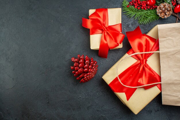 Vista aérea del estado de ánimo navideño con conos de coníferas y ramas de abeto de regalo en el lado derecho de la mesa oscura