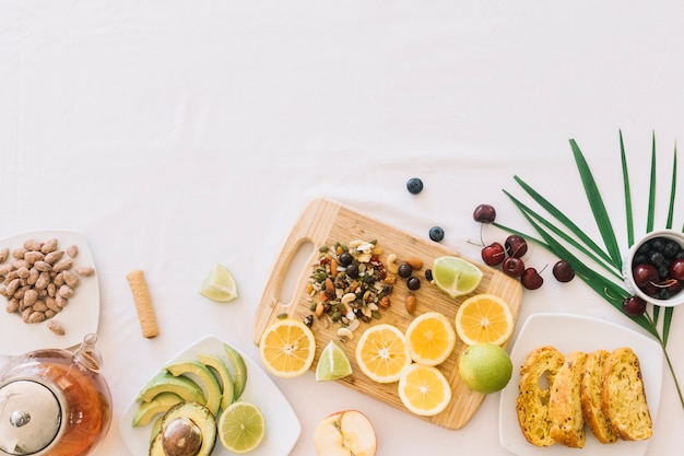 Una vista aérea de la fruta; té; Pan y frutos secos sobre fondo blanco