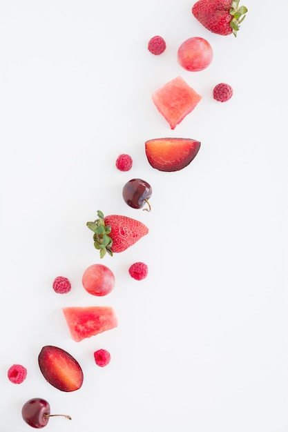 Una vista aérea de frutas rojas diagonales con espacio de copia para escribir texto sobre fondo blanco