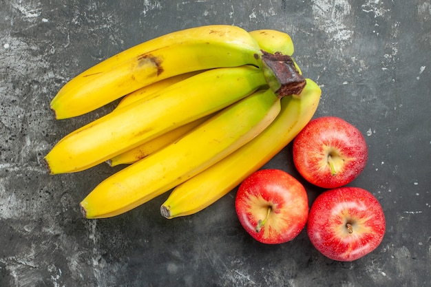 Vista aérea de la fuente de nutrición orgánica paquete de plátanos frescos y manzanas rojas sobre fondo oscuro