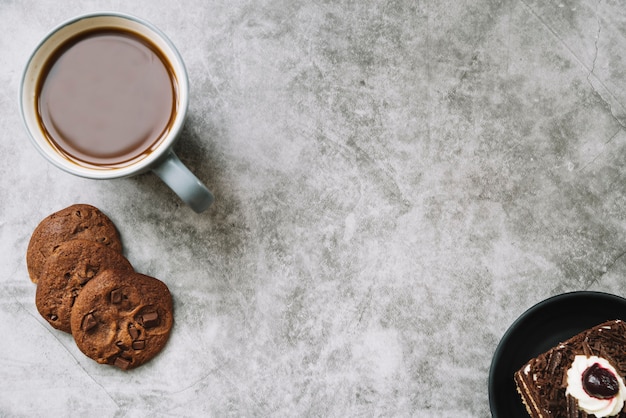 Una vista aérea de galletas; pastel y taza de café en un viejo telón de fondo