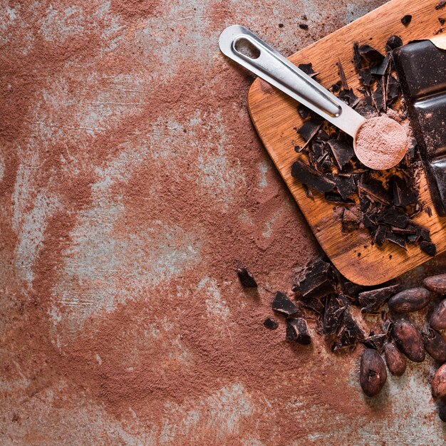 Vista aérea de granos de cacao y barras de chocolate triturado en mesa rústica