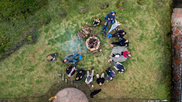 Vista aérea de un grupo de personas que rodean la fogata en el camping.