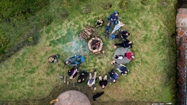 Vista aérea de un grupo de personas que rodean la fogata en el camping.