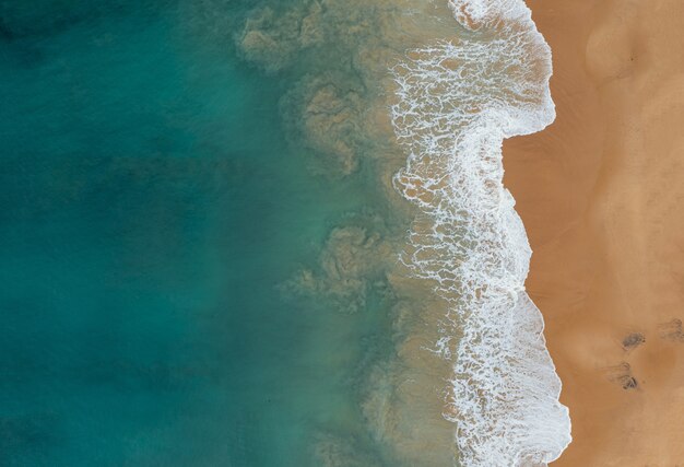 Vista aérea de las hermosas olas del océano que se encuentran con las arenas en la playa