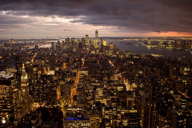 Vista aérea de un hermoso paisaje urbano con edificios iluminados y un mar bajo las nubes de tormenta