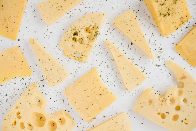 Una vista aérea de las hierbas sobre el queso cheddar en el escritorio blanco