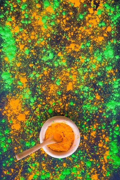 Vista aérea de holi en polvo verde y naranja con tazón
