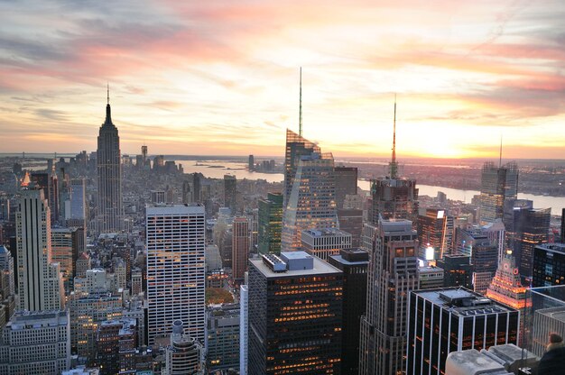 Vista aérea del horizonte de la ciudad de Nueva York al atardecer con nubes coloridas y rascacielos del centro de Manhattan.