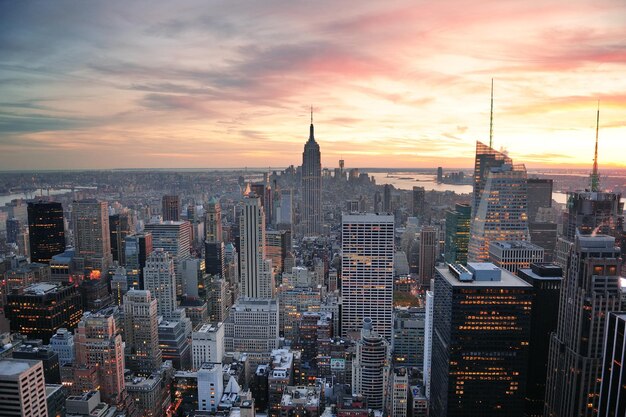 Vista aérea del horizonte de la ciudad de Nueva York al atardecer con nubes coloridas y rascacielos del centro de Manhattan.