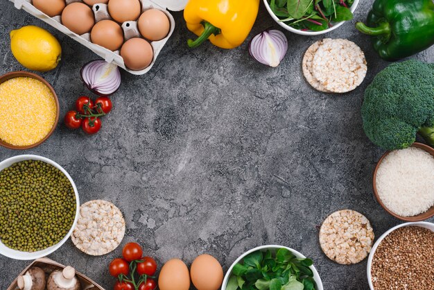 Una vista aérea de los huevos; vegetales; Tazón de polenta y frijol mungo sobre fondo de hormigón