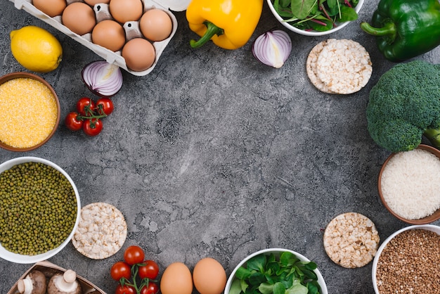 Una vista aérea de los huevos; vegetales; Tazón de polenta y frijol mungo sobre fondo de hormigón