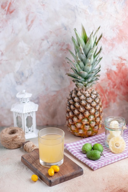 Vista aérea de jugo de fruta fresca y kumquats en una tabla de cortar de madera sobre una toalla despojada de color púrpura, limones cortados enteros y pomelo sobre fondo de colores pastel