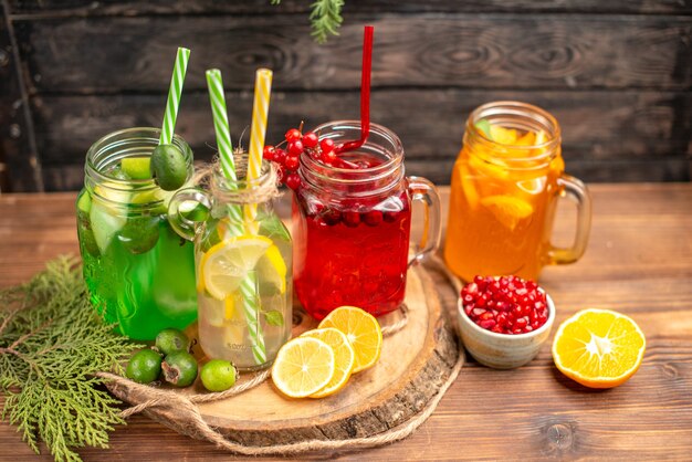 Vista aérea de jugos frescos orgánicos en botellas servidas con tubos y frutas sobre una tabla de cortar de madera sobre una mesa marrón