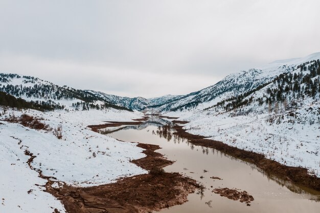 Vista aérea del lago de invierno en montañas nevadas