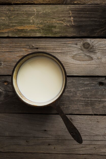 Vista aérea de leche fresca en una cacerola vieja sobre la mesa de madera