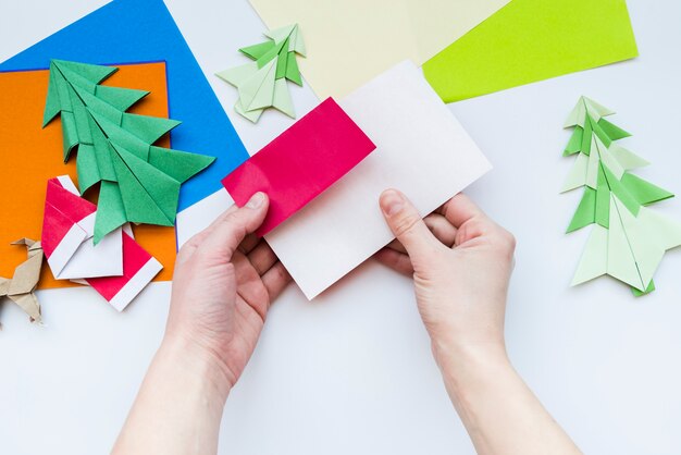 Una vista aérea de la mano de una persona que hace el arte con papel sobre fondo blanco