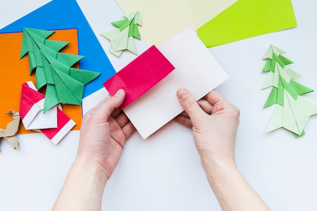 Una vista aérea de la mano de una persona que hace el arte con papel sobre fondo blanco