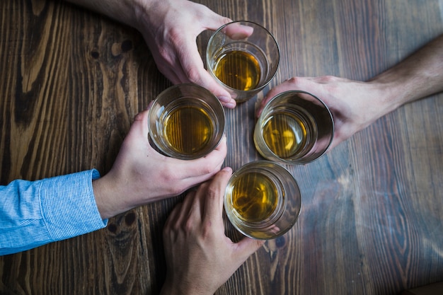 Vista aérea de manos sosteniendo vasos de bebidas en la mesa