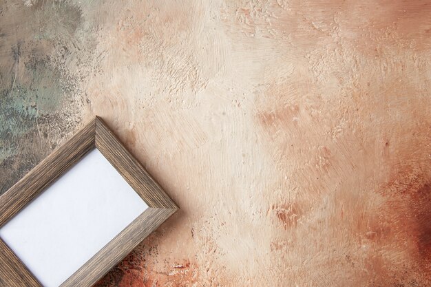 Vista aérea del marco de fotos vacío colgado en una pared de colores mixtos con espacio libre