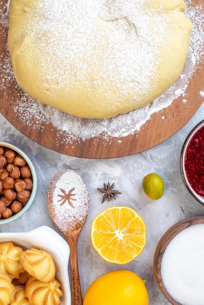 Vista aérea de masa cruda en tablero redondo frutas frescas avena mermelada de fresa avellanas sobre fondo de hielo