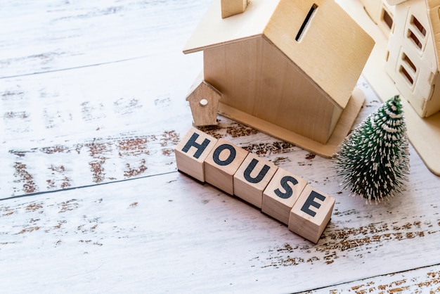 Una vista aérea del modelo de la casa con bloques de madera de la casa y el árbol de navidad en la superficie con textura blanca