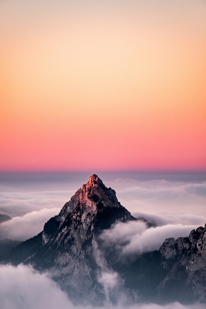 Vista aérea de una montaña cubierta de niebla bajo el hermoso cielo rosado