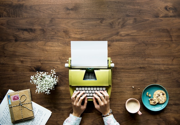 Foto gratuita vista aérea de una mujer escribiendo en un papel en blanco retro máquina de escribir