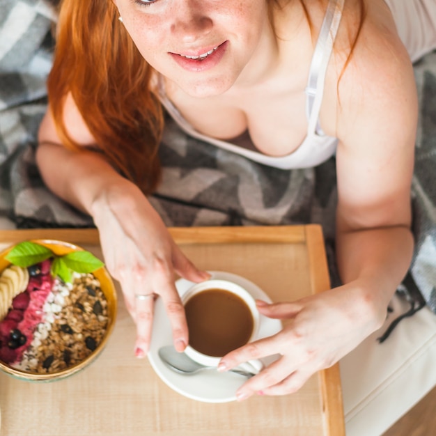 Una vista aérea de la mujer joven sonriente que desayuna sano