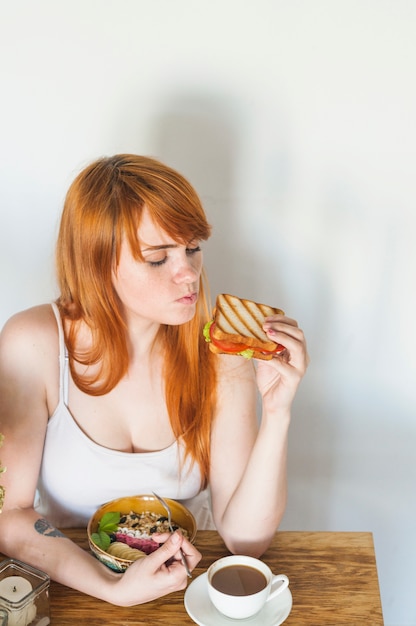 Una vista aérea de la mujer mirando sándwich con tazón de avena