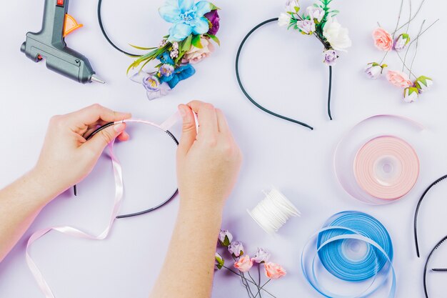 Una vista aérea de una mujer preparando un hairband hecho a mano sobre fondo blanco