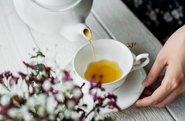 Vista aérea de una mujer que vierte una bebida caliente del té