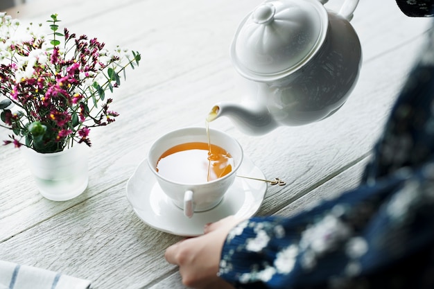 Vista aérea de una mujer que vierte una bebida de té caliente