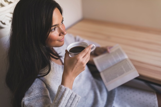 Una vista aérea de una niña sosteniendo un libro tomando café