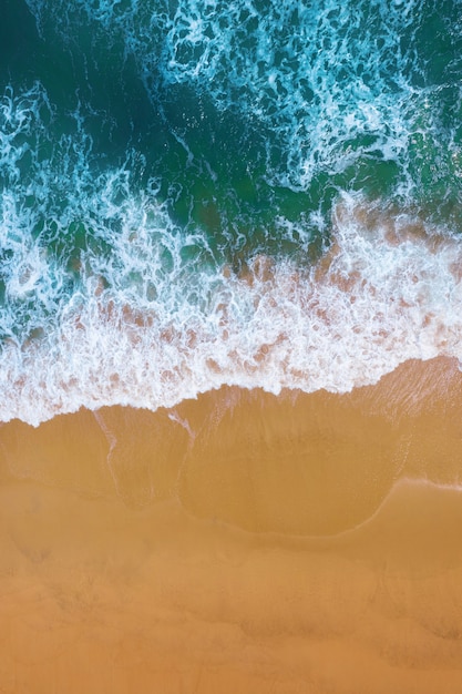 Vista aérea de la ola del océano azul en la playa de arena.