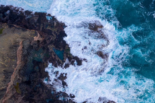 Vista aérea de las olas rompiendo en las rocas